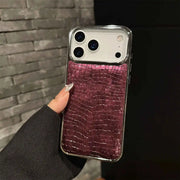 Phone case with purple crocodile texture held by a hand against a dark background