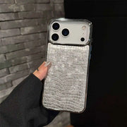 Phone case with crocodile texture held against a dark background