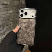 Phone case with crocodile texture held against a dark background
