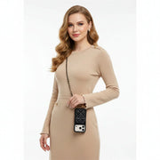 Woman in a beige dress holding a phone in black quilted case with a white background