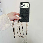Black quilted phone case with card holder a chain strap held by a hand on a white background