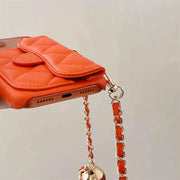 Orange quilted phone case with chain strap on a light gray background