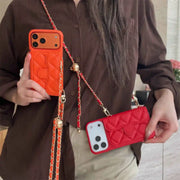 Person holding two designer phone cases with chains, one orange and one red.
