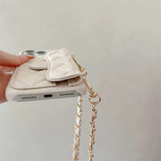 Phone case with chain strap held by a hand on a light background