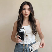 Woman holding two designer crossobdy phone cases, one black and one white, against a beige background