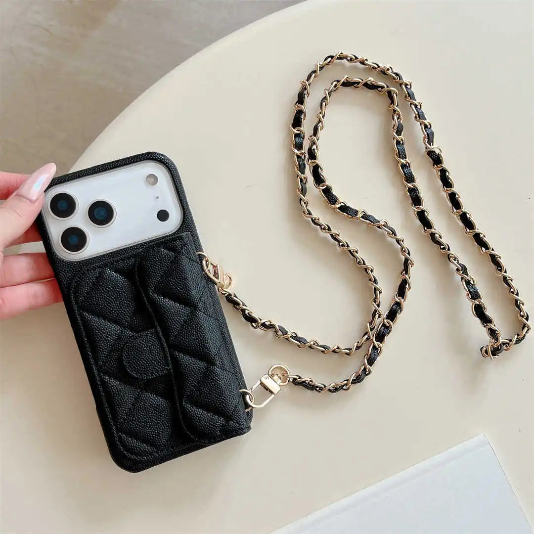 Black quilted phone case with a chain strap held by a hand on a light surface.