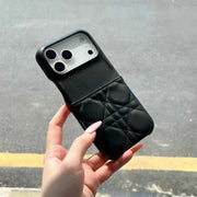 Black quilted phone case held by a hand on a gray pavement background