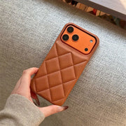 Brown quilted phone case held by a hand on a textured surface