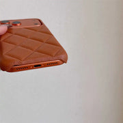 Brown quilted phone case held by a hand against a light gray background