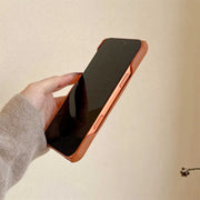 Hand holding a smartphone with a brown case against a beige background