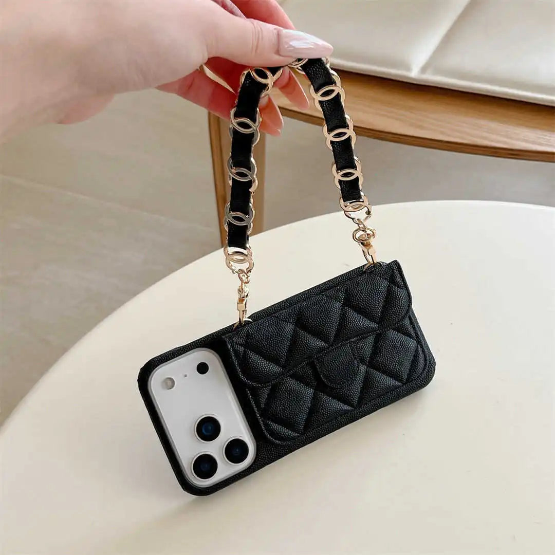 Black quilted phone case with chain strap held by a hand