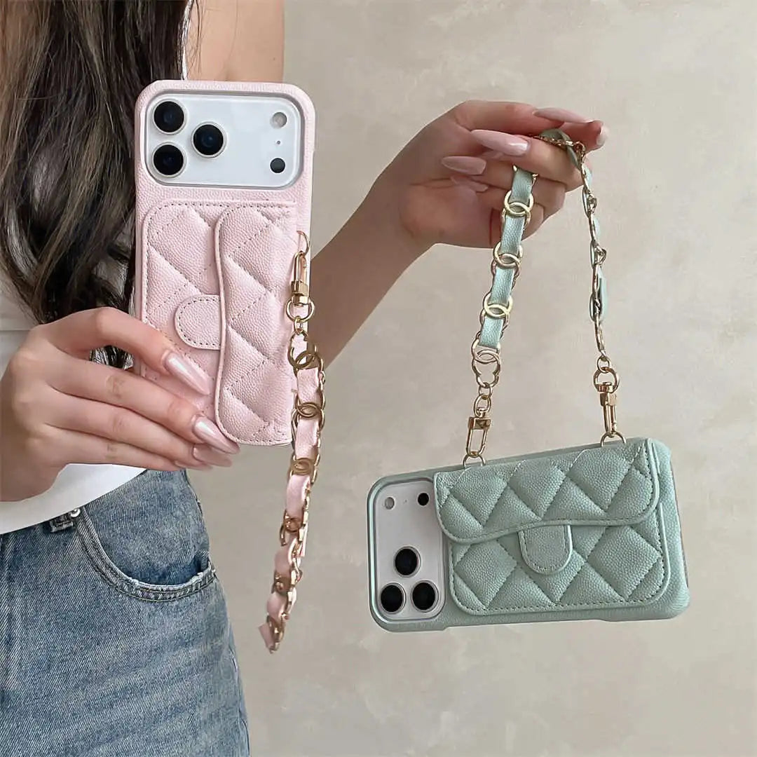 Two phone cases, one pink and one green, with chain straps held by a person.