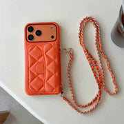 Orange quilted phone case with a matching chain on a white surface