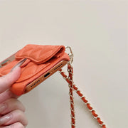 Orange phone case with chain strap held by a hand on a light background