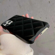 Black quilted phone case held by a person against a neutral background