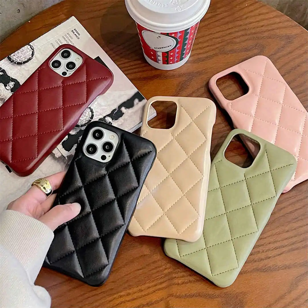 Five quilted phone cases in different colors on a wooden table with a coffee cup.