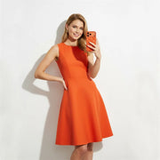 Woman in an orange dress taking a selfie against a white background